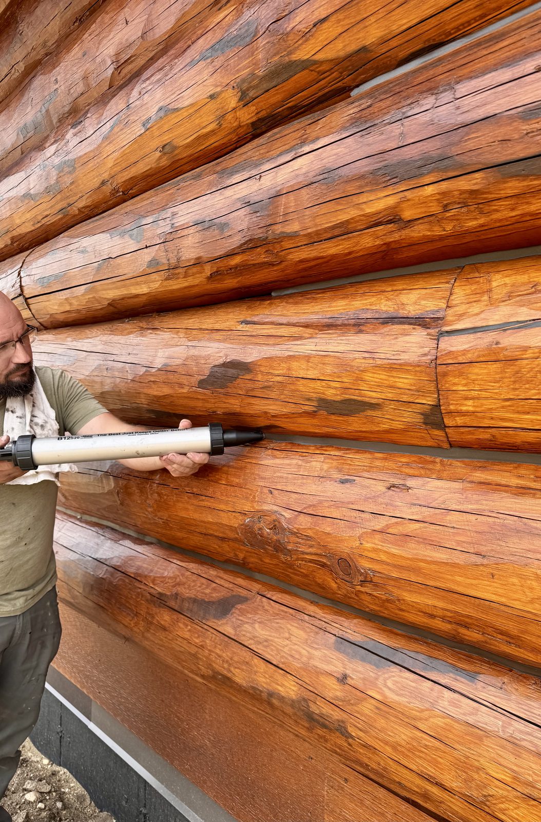 Dennis Bontrager applying chinking to log home Northwest Montana